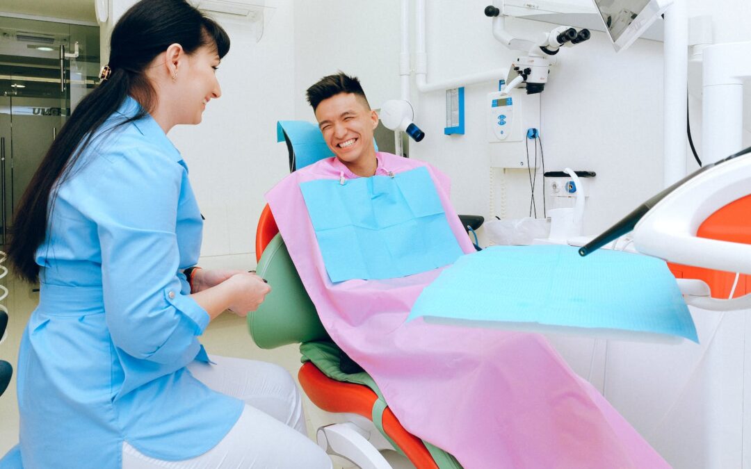 Cheerful ethnic male patient sitting in dental chair in clinic